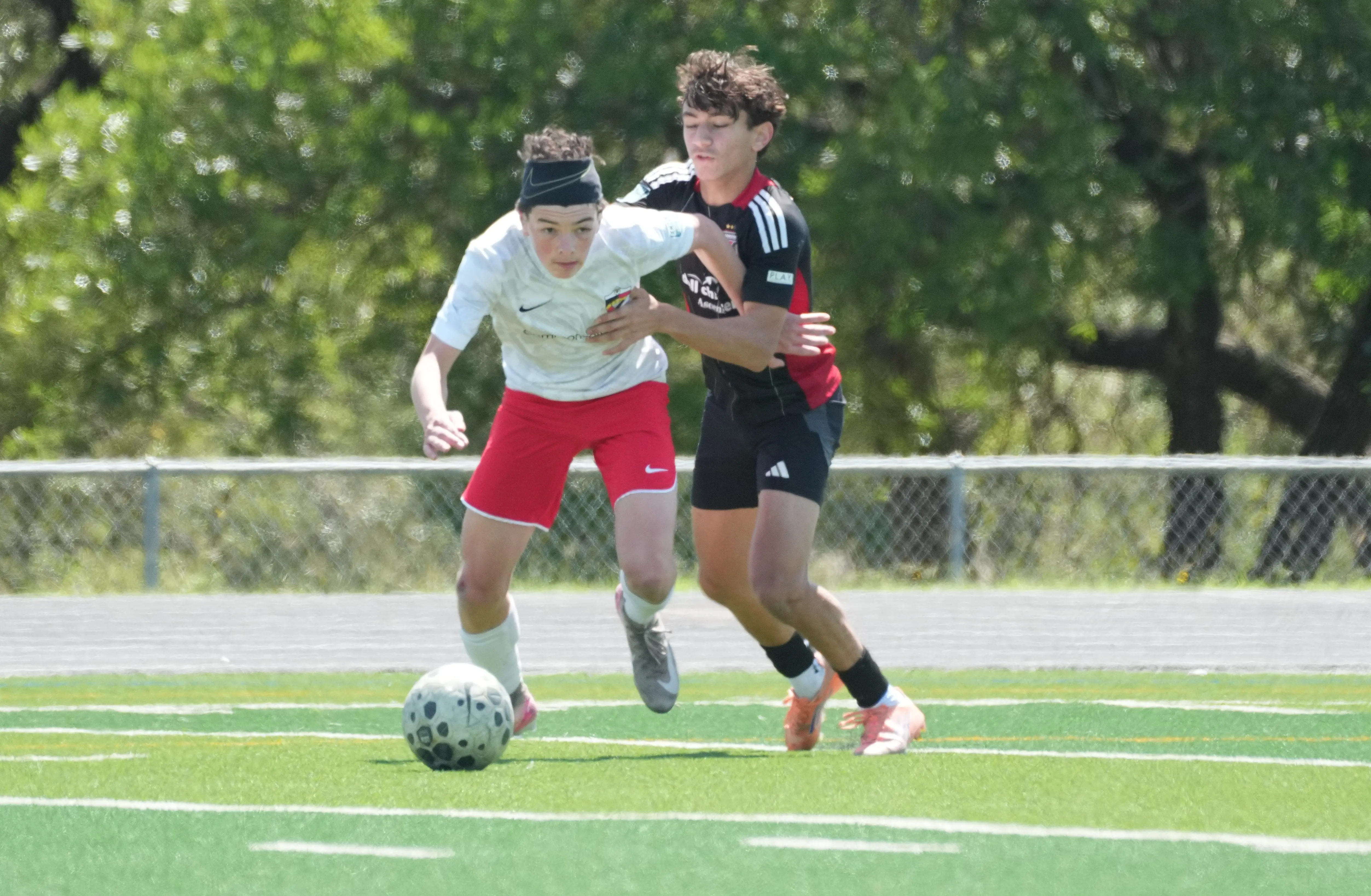 Daylen Hammon in white Real Colorado kit with black headband shielding ball from Lonestar defender in black kit April 2026